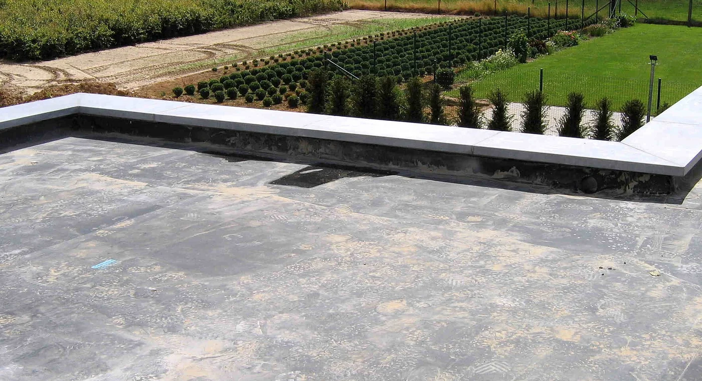 Low-slope EPDM membrane roof with parapet edges and a drainage outlet