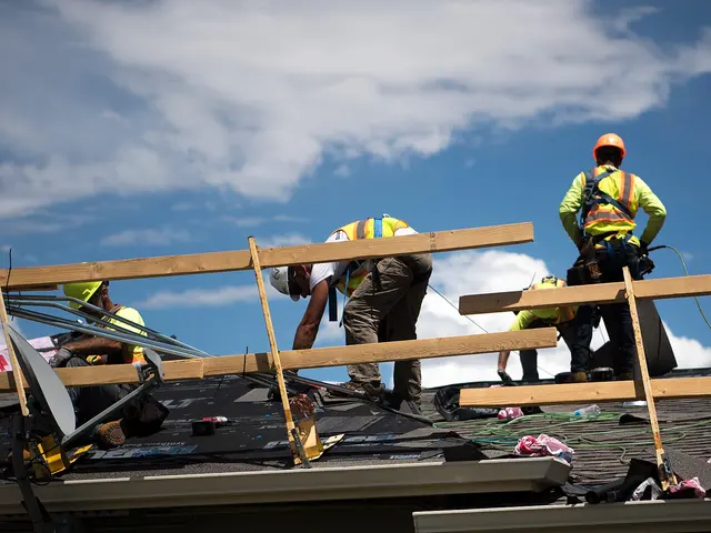 Roofing crew in safety vests working on a roof under a blue sky