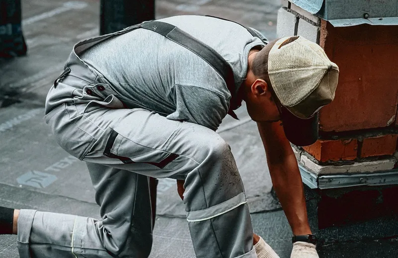 Roofer working around chimney flashing on a rooftop