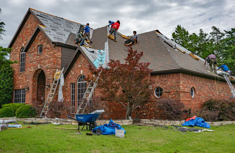 Roofing crew replacing the roof on a brick home